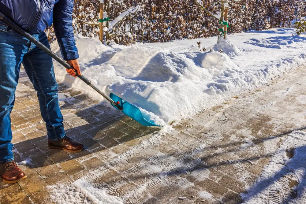 Gehweg wird mit der Schneeschaufel geräumt – Westfalia Winterdienst